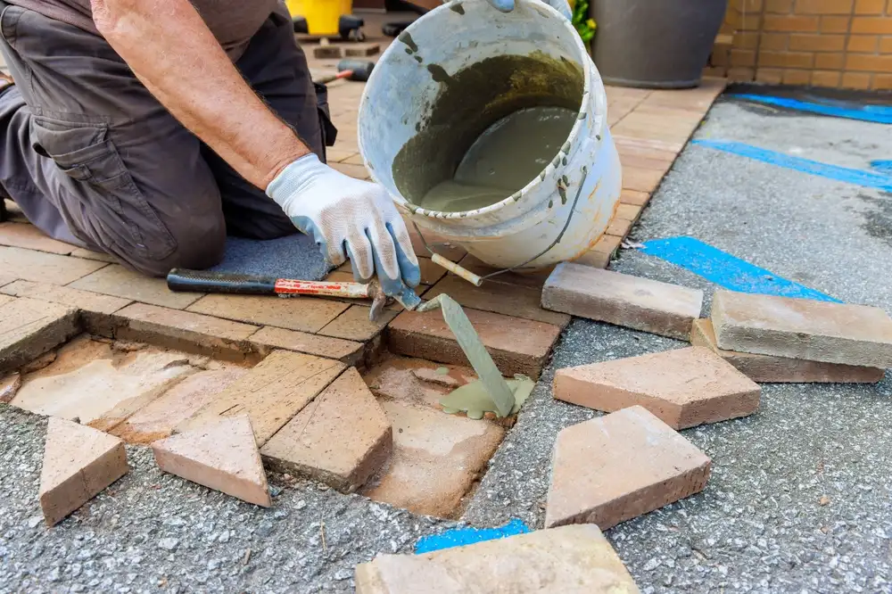 Contractor repairing and replacing damaged concrete and brick surfaces on homes.