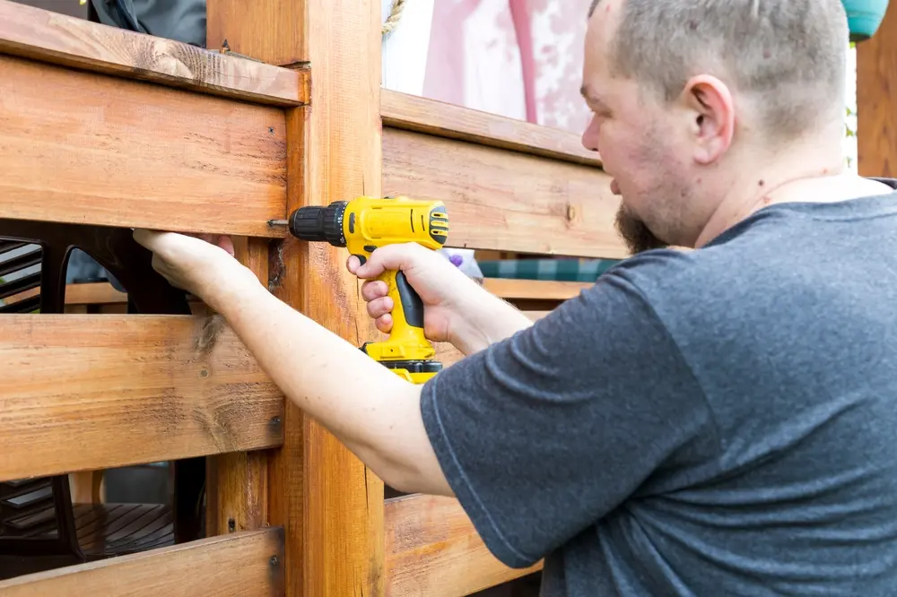 Contractor installing and repairing a wooden fence around a residential property