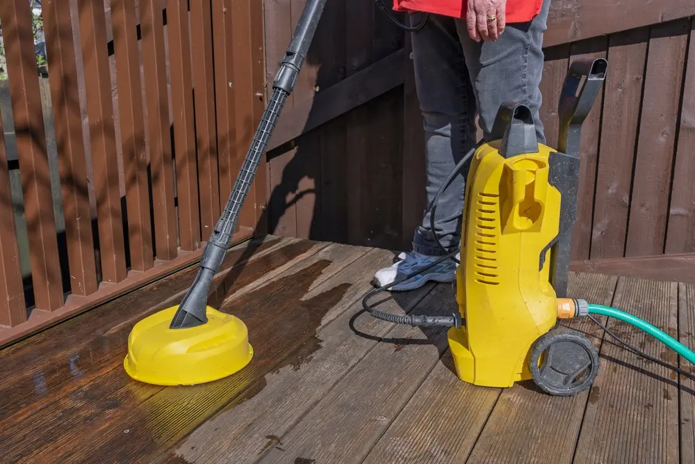Professional contractor power washing a wooden deck to remove dirt, stains, and weathering buildup